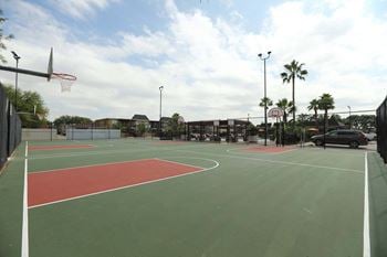 A basketball court with a red and green surface and a basketball hoop.